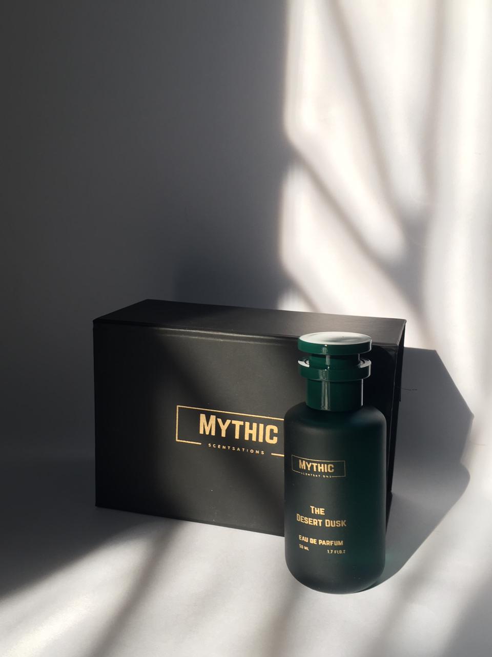 Green perfume bottle with 'Mythic' branding on a black box against a gray background